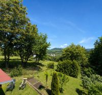 Der Garten der Hütte auf Klučina in Považská Bystrica mit üppigem Grün und Stühlen.