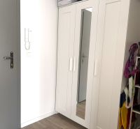 Einbauschrank mit weißen Türen und Spiegel in einer Einzimmerwohnung.