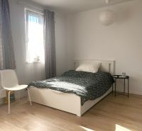 Helles Zimmer in einer Einzimmerwohnung mit Bett und Holzboden.