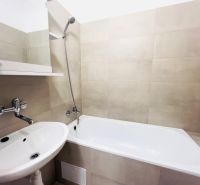 Badezimmer in einer 2-Zimmer-Wohnung mit Badewanne, Waschbecken und hellen Keramikfliesen.