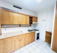 Küche in einer 2-Zimmer-Wohnung mit Keramikfliesen und Holzschränken.