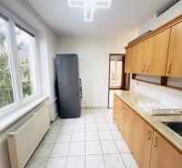 Küche in einer 2-Zimmer-Wohnung mit Fenstern, Fliesen und Holzdekor der Schränke.