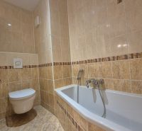 Badezimmer mit gefliesten Wänden und Badewanne in einer 4-Zimmer-Wohnung.