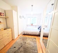 Helles Schlafzimmer in einer 2-Zimmer-Wohnung mit Holzboden und Spiegelschrank.