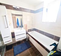 Badezimmer in einer 2-Zimmer-Wohnung mit Badewanne, Dusche und weißen Möbeln.