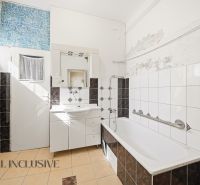Badezimmer in einem Einfamilienhaus mit weißer Badewanne und Mosaikfliesen.