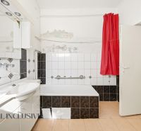 Ein Badezimmer in einem Einfamilienhaus mit einer Badewanne, weißen Fliesen und einem roten Vorhang.
