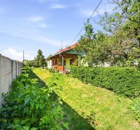 Ein Einfamilienhaus in Hviezdoslavov mit Garten, grünen Sträuchern und einer Rasenfläche neben einem Betonzaun.