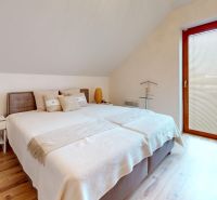 Ein Schlafzimmer in einer Hütte mit einem bequemen Bett, Holzelementen und einem Boden mit Holzdekor.
