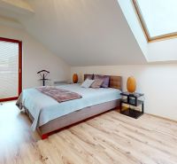 Ein Schlafzimmer mit einem Doppelbett, einem Dachfenster und einem Holzboden in einer Hütte.
