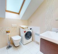 Badezimmer in der Hütte mit Waschmaschine, Badewanne, Toilette und Waschbecken, helle Fliesen.