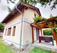 Ein Ferienhaus in Moča in der Straße Moča mit Terrasse und Holzpergola, umgeben von einem Garten.