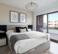 Schlafzimmer in einer 2-Zimmer-Wohnung mit großem Fenster, Kunst an der Wand und komfortablem Bett.