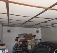 Garagen mit einem weißen Ventilator, gelagerten Gegenständen und einem geparkten Auto.