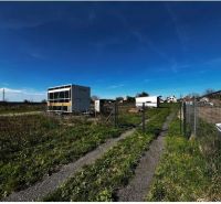 Grundstücke - Wohnen in Pernek mit Containern, Zäunen und einem grasbewachsenen Weg auf dem Land.