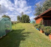 Der Garten eines Einfamilienhauses in Bacúch mit Folientunneln und einem Pavillon, umgeben von Pflanzen.