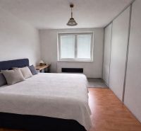 Schlafzimmer mit großem Bett und Holzboden in einem Einfamilienhaus.