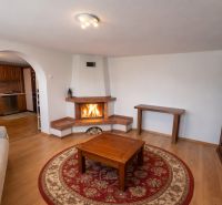 Wohnzimmer in einem Einfamilienhaus mit Kamin, Holzboden und einem bogenförmigen Durchgang.