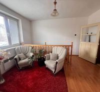 Innenraum eines Einfamilienhauses mit Sofas, rotem Teppich und Holzboden.