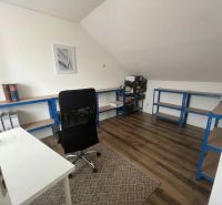 Büro in einem Einfamilienhaus mit Holzboden, Regalsystem und Schreibtisch.