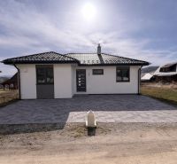 Ein Einfamilienhaus in Ižipovce mit Parkplätzen und einem Ziegeldach unter einem sonnigen Himmel.