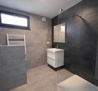 Modernes Badezimmer mit Keramikfliesen und großer Duschkabine in einem Einfamilienhaus.