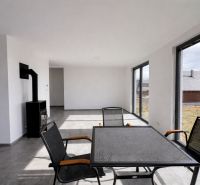 Wohnzimmer in einem Einfamilienhaus mit Kamin, großen Fenstern und schwarzen Möbeln.