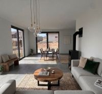 Wohnzimmer in einem Einfamilienhaus mit Kamin, hellen Möbeln und Holzboden.
