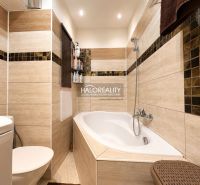 Badezimmer mit Badewanne, moderner Fliese und WC in einer Einzimmerwohnung.