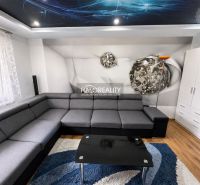 Wohnzimmer in einer Einzimmerwohnung mit Ecksofa, Boden in Holzoptik und dekorativer Decke.