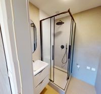 Badezimmer in einer 2-Zimmer-Wohnung mit verglaster Duschkabine und Waschbecken.