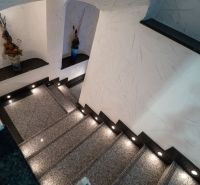 Eine Treppe mit Beleuchtung, verziert mit Vasen, texturierte Wände in einer besonderen Immobilie.