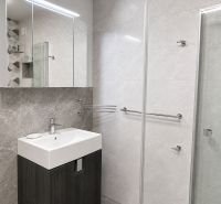 Badezimmer mit Waschbecken, Spiegel und Duschkabine in einer 3-Zimmer-Wohnung.