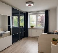Ein Zimmer in einer 3-Zimmer-Wohnung mit einem Boden in Holzoptik und einem großen Kleiderschrank.