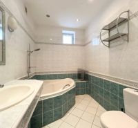 Badezimmer in einem Einfamilienhaus mit Badewanne, Waschbecken, Spiegel und Toilette.