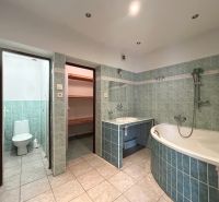 Badezimmer in einem Einfamilienhaus mit Badewanne, grünen Fliesen und Zugang zur Toilette.