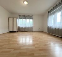 Innenraum eines Einfamilienhauses mit Holzboden und zwei Fenstern.