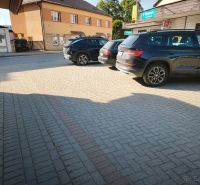 Parkplatz bei Geschäftsräumen in Turzovka mit Autos auf dem Pflaster.