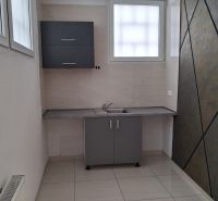 Büros mit Küchenzeile, Fliesen und grauem Schrank, geeignet für eine Arbeitsumgebung.