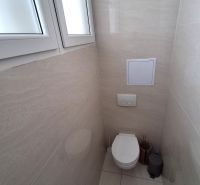 Badezimmer im Büro mit geschlossenem WC und einfachen Fliesen.