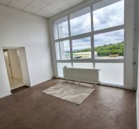 Ein Büro mit einem großen Fenster, einem Boden mit Holzdekor und Fußbodenheizung.
