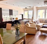 Küche mit weißen Möbeln, Ledersofa, Boden mit Holzdekor in einer 3-Zimmer-Wohnung.