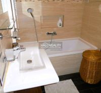 Badezimmer mit Waschbecken, Badewanne und Korb in einer 3-Zimmer-Wohnung.
