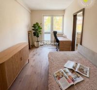 Helles Zimmer mit Holzboden und Möbeln in einer 3-Zimmer-Wohnung.