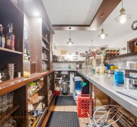 Innenraum eines Gastronomiebereichs mit Bar und Getränken auf den Regalen, Boden mit Holzdekor.