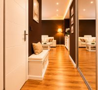Der Flur in einer 2-Zimmer-Wohnung mit einem Boden in Holzoptik und einer bequemen Sitzgelegenheit.
