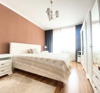 Hauptschlafzimmer in einer Zweizimmerwohnung mit Bett und Boden in Holzoptik.