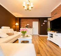 Wohnzimmer in einer 2-Zimmer-Wohnung mit Holzboden und weißen Möbeln.