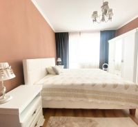 Schlafzimmer in einer 2-Zimmer-Wohnung mit einem Doppelbett, weißen Möbeln und einem Boden mit Holzdekor.