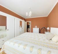 Schlafzimmer in einer 2-Zimmer-Wohnung mit weißen Möbeln und einem Bett auf dem Boden mit Holzdekor.